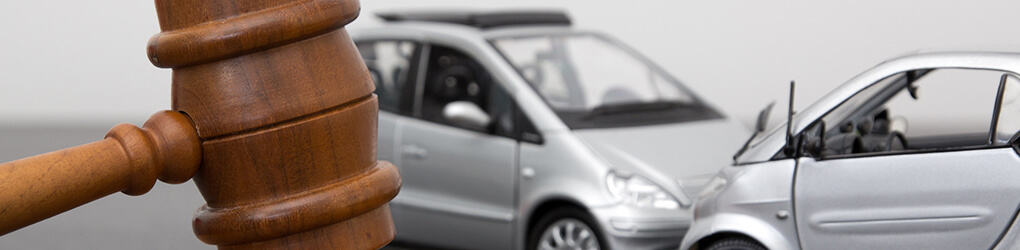 two cars colliding in an accident in the background with a gavel in the foreground