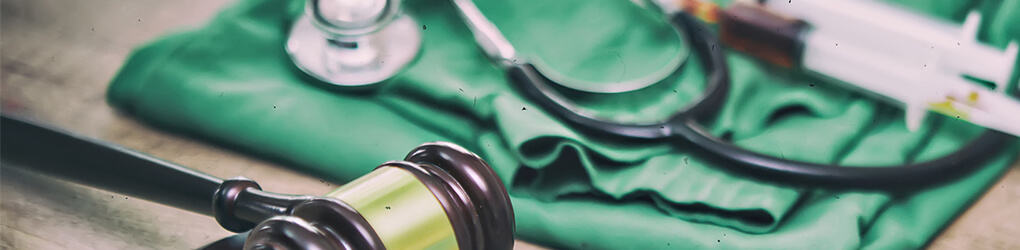 a gavel next to scrubs and a stethoscope on a table