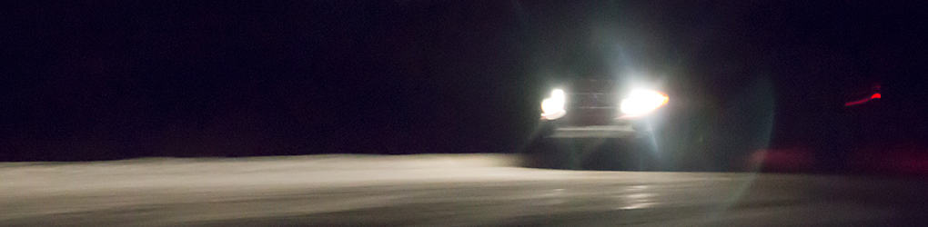 view of a car's headlights on while driving on a road in the dark