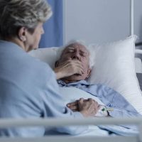 Elderly man with lung cancer lying in a hospital bed and coughing