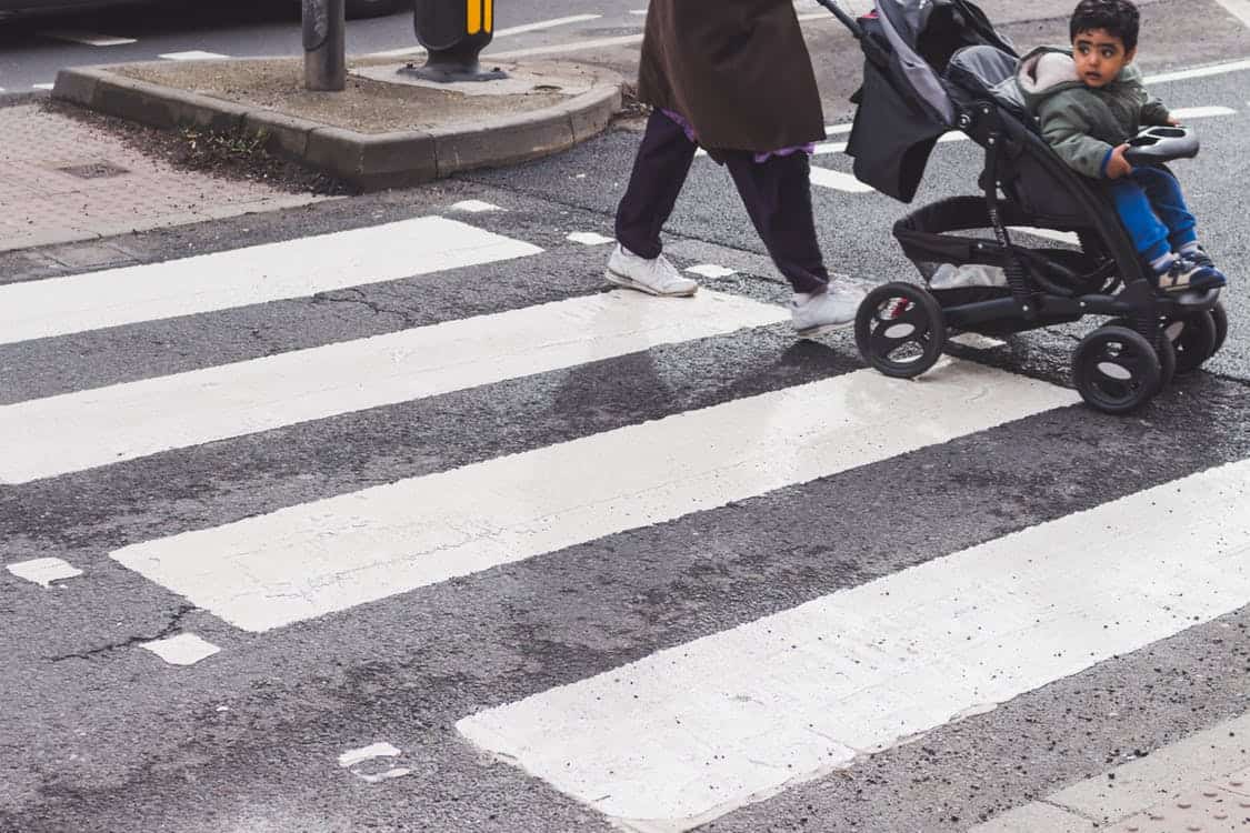 child being pushed in a stroller across a crosswalk