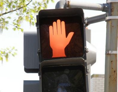 red stop sign hand lit up in a crosswalk