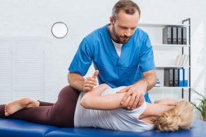 chiropractor adjusting a patient's back while in their office