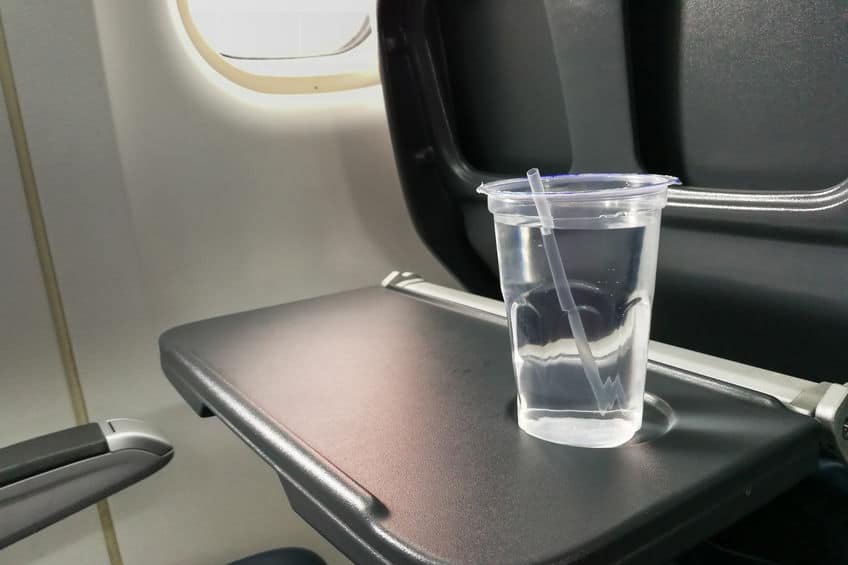 a cup of water sitting on a tray table in an airplane