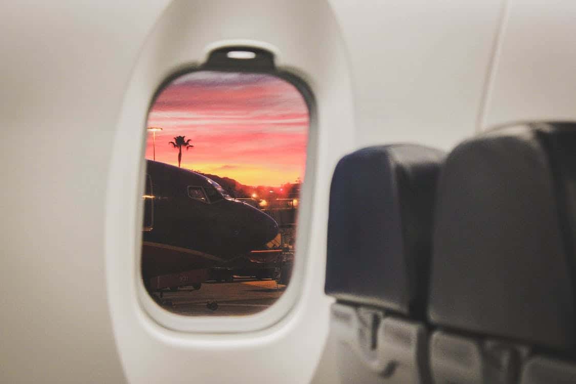 the view from a passenger's perspective looking out the window of an airplane at another plane and a sunset in the background