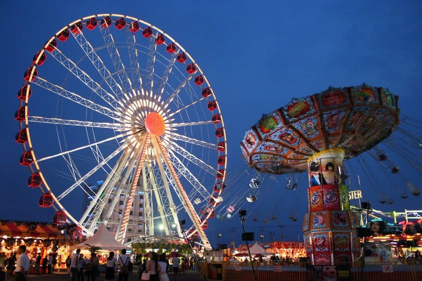 a carnival with a ferris wheel and swing ride lit up