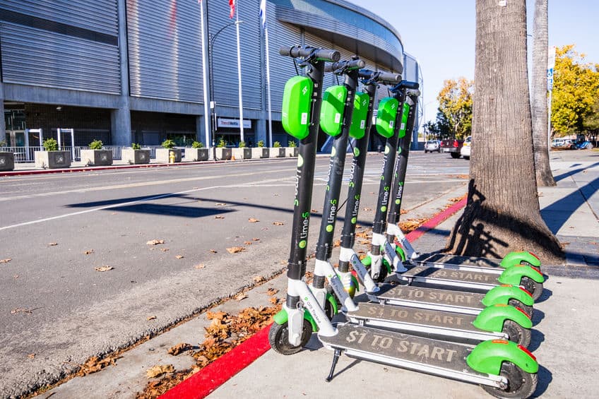 lime green scooters lined up on a sidewalk in downtown San Jose, south San Francisco bay area