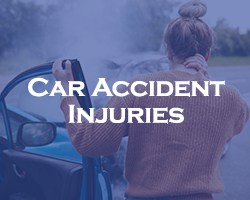 Car Accident Injuries -- blue overlay on a woman holding her neck after being in a car accident and standing next to her damaged car