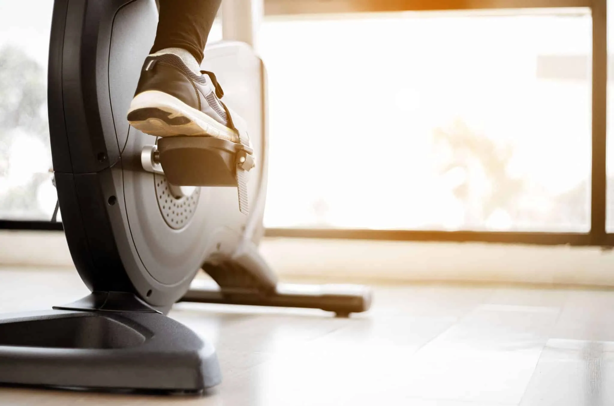 Close up foot biking in gym, exercising legs doing cardio workout cycling bikes.